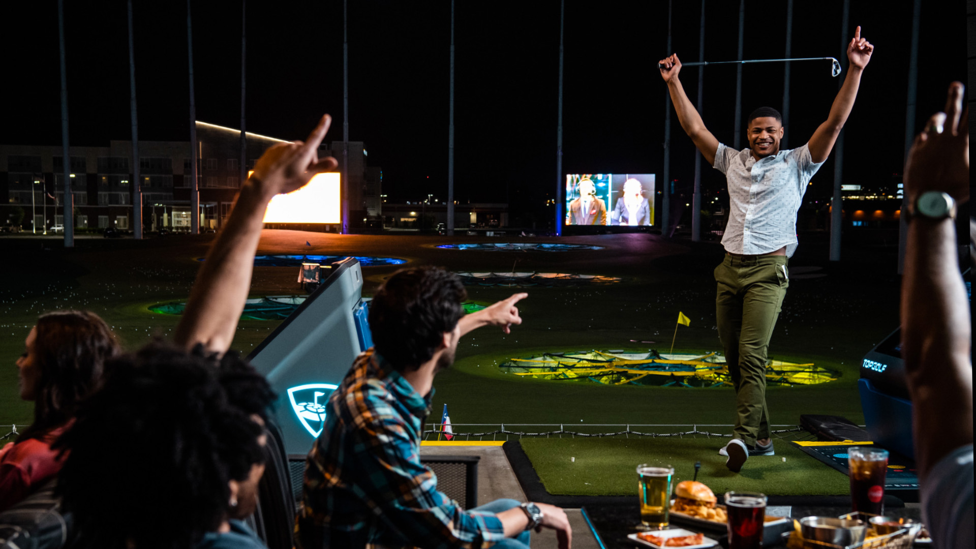 Players celebrating in a bay at Topgolf